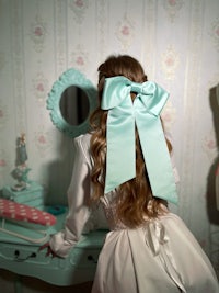 a girl in a white dress with a blue bow in her hair