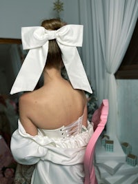 a woman in a white dress with a bow in her hair