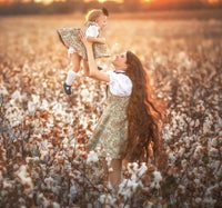 a woman and her daughter in a cotton field at sunset